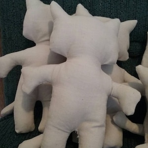 May include: Three unstuffed white fabric cat toys. The toys are made of a soft, natural fabric and have a simple, classic design.