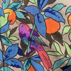 May include: A fabric featuring a repeating pattern of a purple bird perched on a branch amidst bright orange fruit and blue and green leaves. The background is a neutral beige colour, and the design uses bold black outlines for all elements.