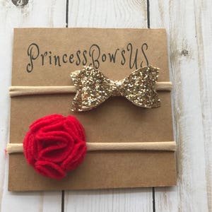 May include: Two baby headbands on a brown card. One headband has a gold glitter bow, and the other has a red felt flower. The card has the text "Princess Bows US" in black script.