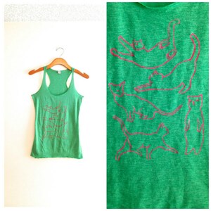 May include: Green tank top with a pink outline of multiple cats in different poses. The tank top is made of a soft, comfortable material.
