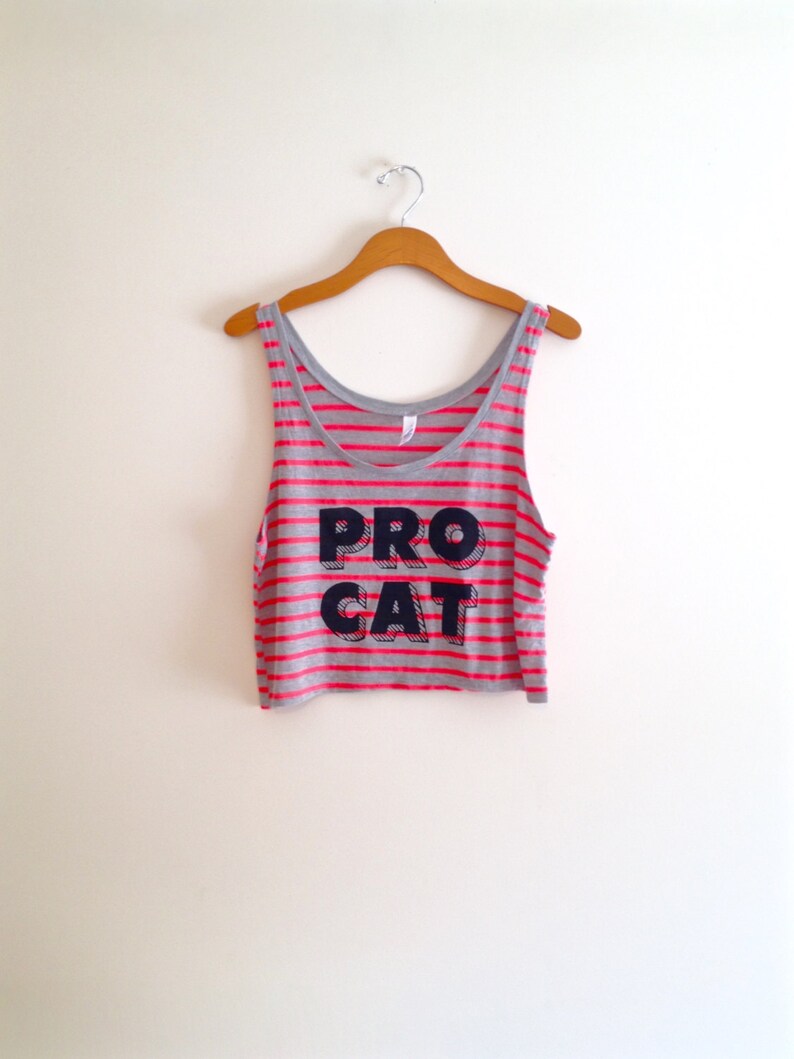 Op de afbeelding: Een grijs en roze gestreept tanktop met de tekst "PRO CAT" in zwarte letters.