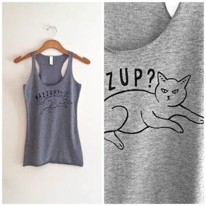 May include: Gray tank top with a black cat illustration and the text "Wazzup?" on the front. The back of the tank top has a black cat illustration and the text "Zup?"