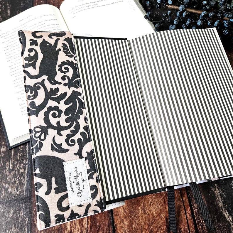 May include: A black and white book cover with a black and white striped pattern. The cover is handmade by Elizabeth Mayfair.