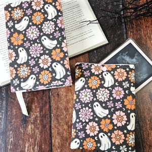 May include: Two book covers with a black background and a repeating pattern of white ghosts, orange and pink flowers, and white stars.