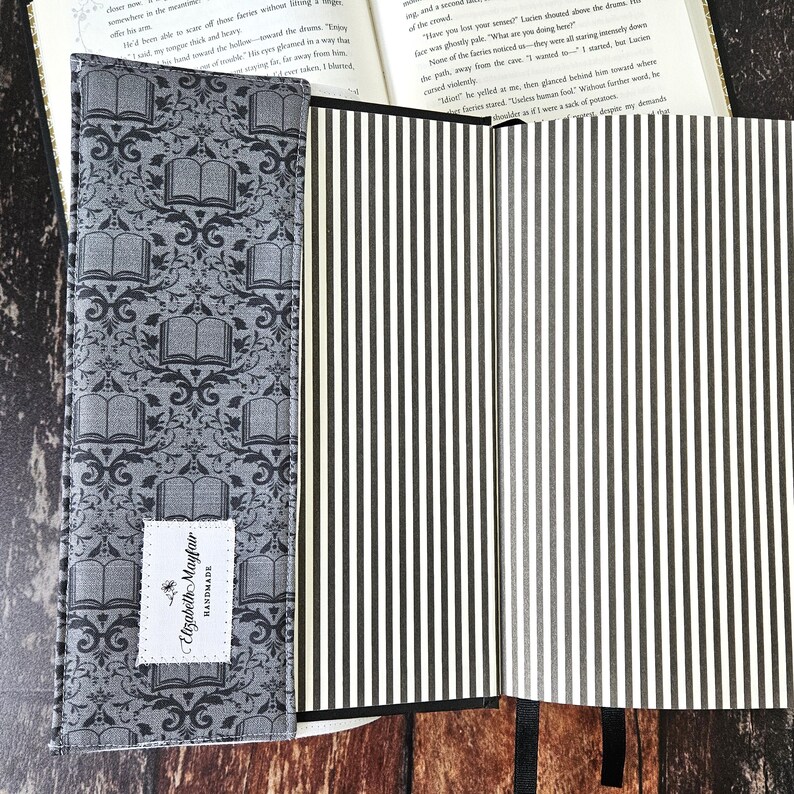 May include: A gray and black fabric book cover with a damask pattern and the text "Elizabeth Mayfair HANDMADE". The cover is open to reveal a white and black striped interior.