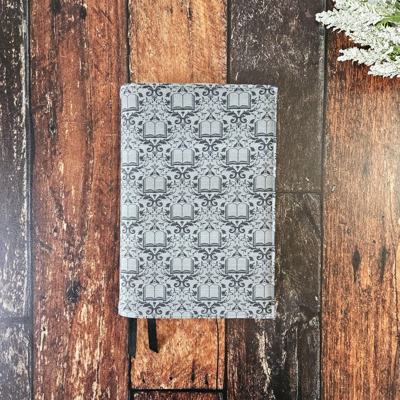 May include: A gray book cover with a repeating pattern of black books and floral designs.