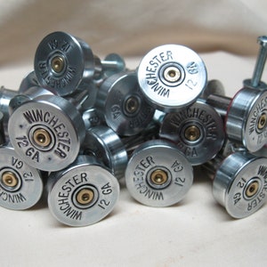 May include: A close-up of a pile of silver shotgun shell drawer pulls. The shells are marked with "Winchester" and "12 GA".