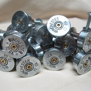 May include: A close-up of a pile of silver shotgun shell drawer pulls. The shells are marked with "Winchester" and "12 GA".