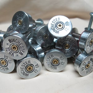 May include: A close-up of a pile of silver shotgun shell drawer pulls. The shells are marked with "Winchester" and "12 GA".