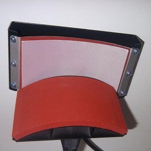 May include: A black heat press with a red and white heat plate. The heat plate is curved to fit a mug or other round object.