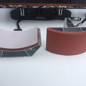 May include: Two curved heat press plates, one with a white fabric cover and the other with a red rubber cover. Both plates are made of aluminum and have a silver finish.