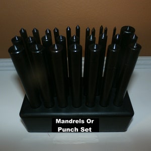 May include: A set of black metal mandrels or punches in a black plastic holder. The holder has the text "Mandrels Or Punch Set" printed on it.