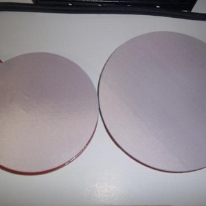 May include: Two round, white, adhesive pads with red edges. The pads are attached to black cords.