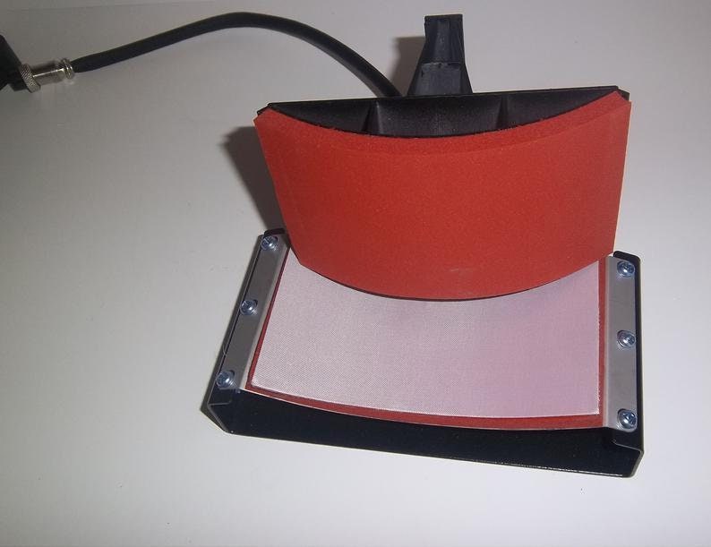 May include: A black heat press with a red silicone pad and a white Teflon sheet. The press is open and ready to use.