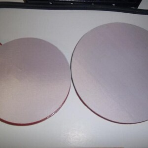 May include: Two round, white, adhesive pads with red edges. The pads are attached to black cords.