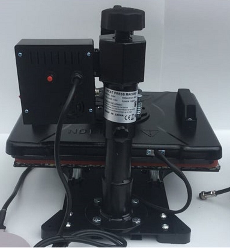 May include: Black heat press machine with a control panel and a lever. The machine is on a black base with a red heat resistant pad. The machine has a label that says "Heat Press Machine" and "Made in China".