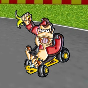 Pu&ograve; includere: Un personaggio dei cartoni animati rosso e giallo che guida un kart giallo. Il personaggio ha la pelliccia marrone, una camicia rossa e una banana in mano.
