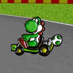 Pu&ograve; includere: Un personaggio verde Yoshi della serie Super Mario che guida un kart nero e verde con un guscio verde nella parte posteriore.