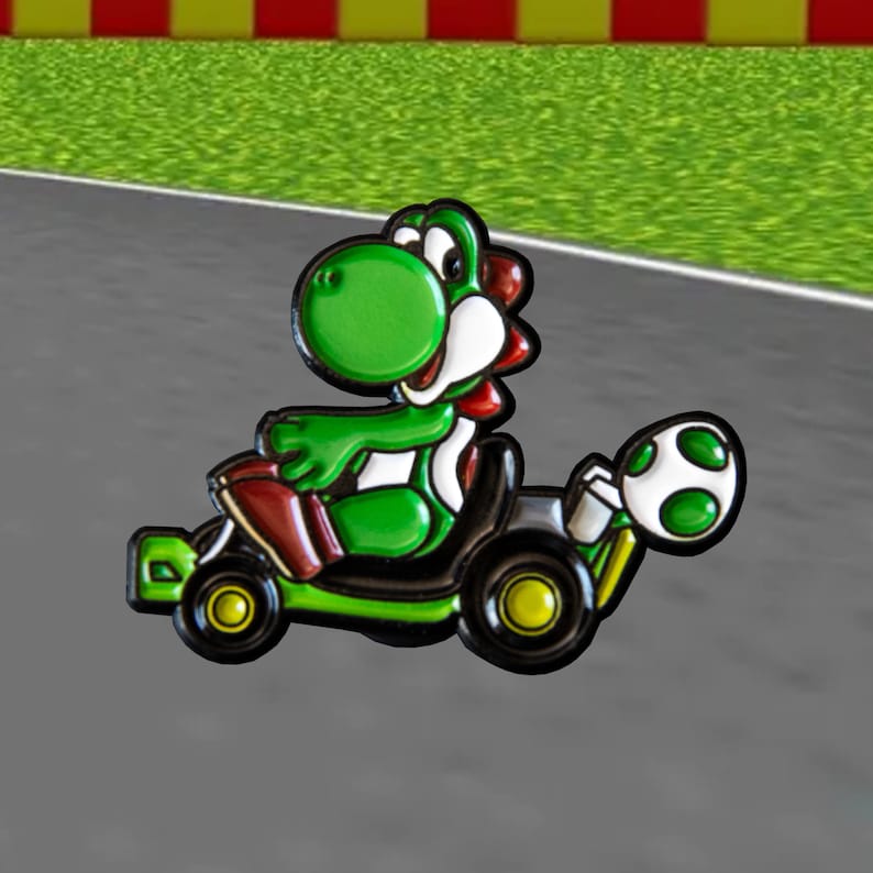 Pu&ograve; includere: Un personaggio verde Yoshi della serie Super Mario che guida un kart nero e verde con un guscio verde nella parte posteriore.