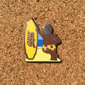 May include: A brown bear wearing red and yellow swim trunks and sunglasses is holding a yellow surfboard with the word "GRIZZ" written on it. The bear is standing on a beach with blue and white waves in the background.