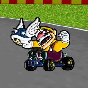 Pu&ograve; includere: Un personaggio dei cartoni animati giallo e viola con un'ala bianca e un baffo, che guida un kart blu e nero.