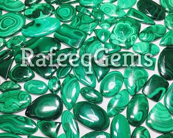 May include: A collection of polished malachite gemstones in various shapes and sizes, featuring distinct green banded patterns and swirls. The text RafeeqGems is overlaid in white across the center of the assortment of smooth, shiny stones.