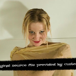 May include: A woman with blonde hair is wearing a sheer gold scarf. She is looking down at the camera with a slight smile.