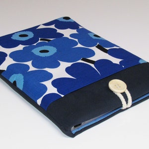 May include: A blue and white floral laptop sleeve with a navy blue flap and a white button closure. The sleeve has a white cord attached to the button.