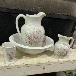 以下が含まれることがあります： 茶色の花柄が施された、ヴィンテージの白いセラミック製のバスルーム用品のセット。セットには、ピッチャー、ボウル、タンブラーが含まれています。