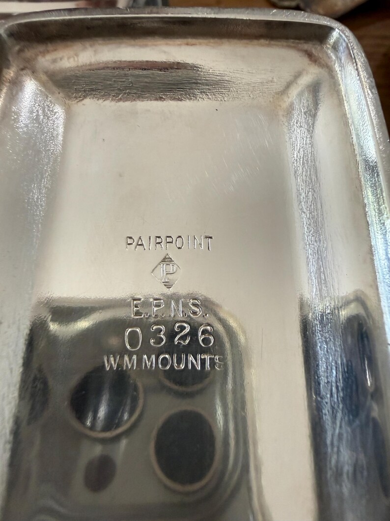 May include: A rectangular, silver-colored tray with rounded corners. The tray has the text "PAIRPOINT" at the top, with the logo of a diamond inside a diamond. Below the logo are the letters "E.P.N.S.", the number "0326", and the text "W.M.MOUNTS".