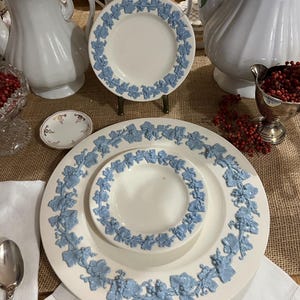 Può includere: Un set di tre piatti in ceramica bianca con un motivo floreale blu. I piatti sono annidati, con il piatto più piccolo in cima. I piatti hanno un bordo rialzato e un bordo smerlato.