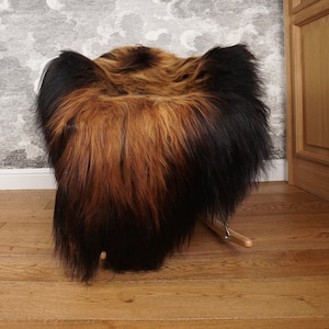 May include: A brown and black fur rocking chair. The chair has a fluffy, textured appearance with a gradient of colors, transitioning from brown to black. The chair is set on wooden rockers.