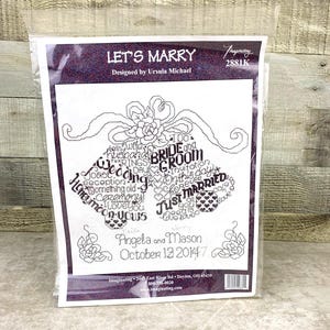 May include: A cross-stitch pattern kit in a clear plastic package. The design features the words "Let's Marry" and a wedding bells motif with the names Angela and Mason and the date October 12, 2014.