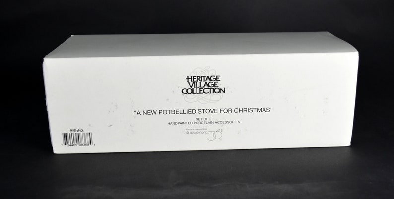 Puede incluir: Caja blanca con texto negro que dice "Heritage Village Collection" y "A New Potbellied Stove for Christmas". La caja tambi&eacute;n dice "Set of 2 Handpainted Porcelain Accessories".