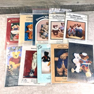 May include: A collection of teddy bear sewing patterns, featuring various designs and styles. The patterns include instructions for creating stuffed bears with different outfits and accessories. The patterns are in clear plastic sleeves.