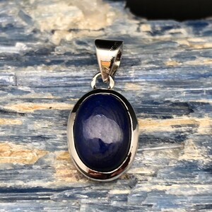 May include: A silver pendant with a dark blue oval lapis lazuli stone.