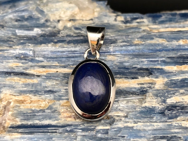 May include: A silver pendant with a dark blue oval lapis lazuli stone.
