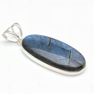 May include: A silver pendant featuring a large oval-shaped labradorite gemstone with blue and black iridescent hues.