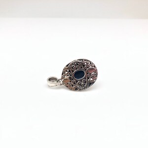 May include: Silver pendant with an oval black stone set in a filigree design.
