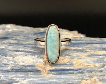 May include: A silver ring featuring a light blue oval-shaped gemstone. The gemstone has a marbled pattern.