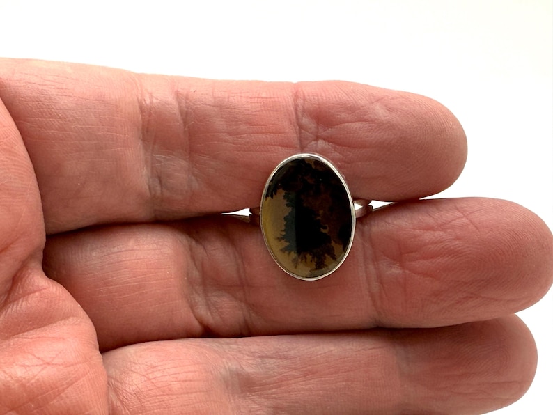 Pu&ograve; includere: Un anello d'argento con una pietra ovale in agata dendritica marrone e nera.