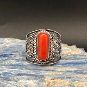 May include: A silver ring with an orange coral stone set in a detailed design.