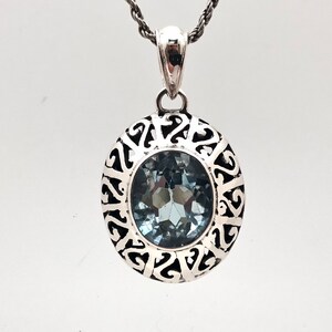 May include: A silver pendant with a blue gemstone set in a filigree design.