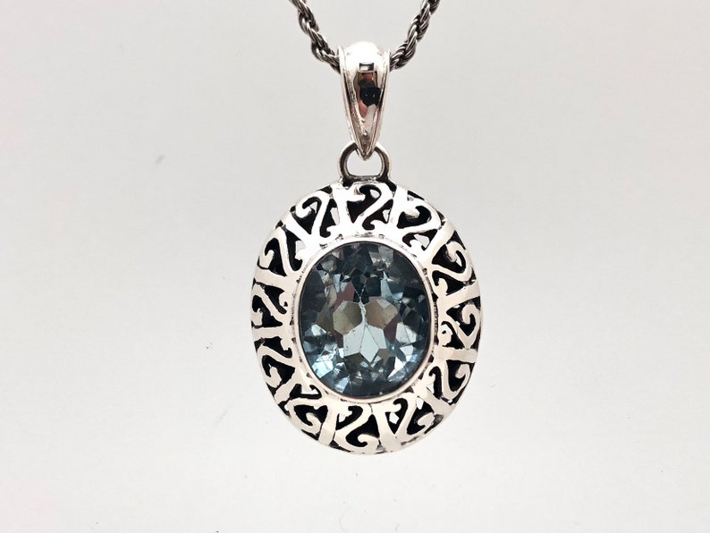 May include: A silver pendant with a blue gemstone set in a filigree design.