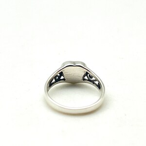 May include: A silver ring with a heart-shaped design and intricate filigree details.