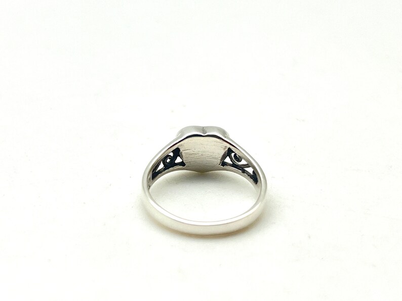 May include: A silver ring with a heart-shaped design and intricate filigree details.