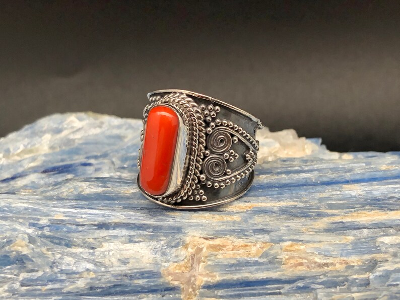 May include: A silver ring with an orange coral stone set in a detailed silver band.