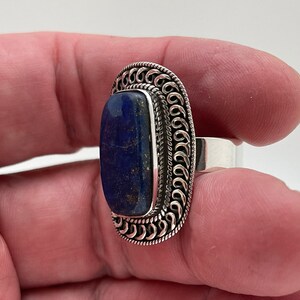May include: A silver ring with a dark blue lapis lazuli stone set in a decorative silver band.