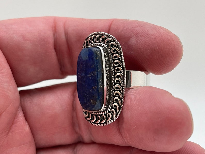 May include: A silver ring with a dark blue lapis lazuli stone set in a decorative silver band.