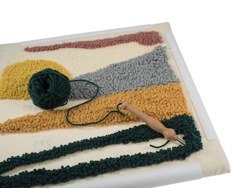 May include: A close-up of a rug hooking project in progress. The rug is made of a variety of colors, including yellow, orange, green, and gray. A wooden rug hooking tool is used to pull the yarn through the fabric. A ball of green yarn is also visible in the image.